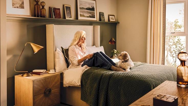 a person sitting on a bed with a dog