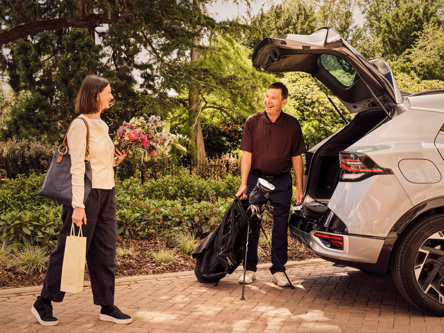 a man and woman standing next to a car with a bag
