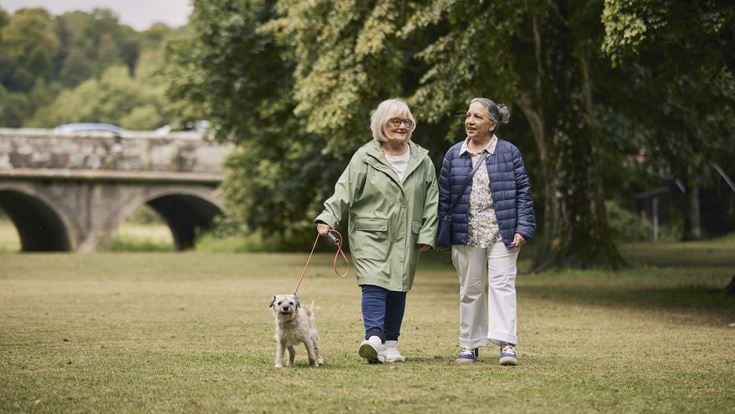a couple of women walking a dog