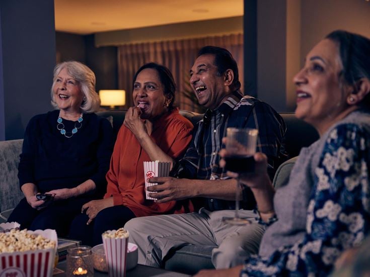 a group of people sitting on a couch and laughing