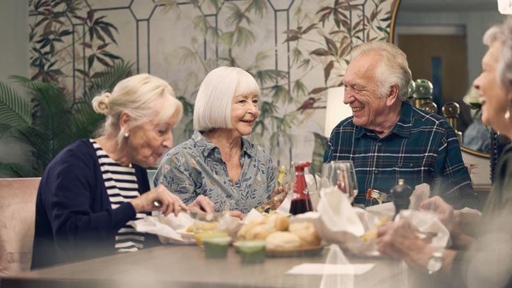 a group of people sitting at a table with food