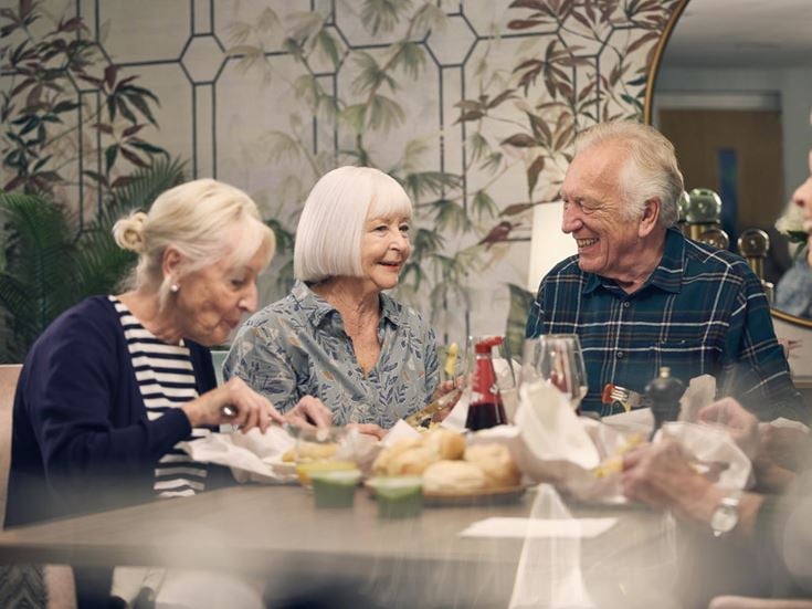a group of people sitting at a table with food