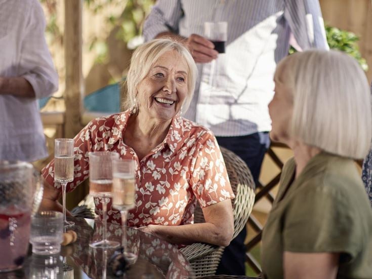 a person smiling at a table with glasses of wine