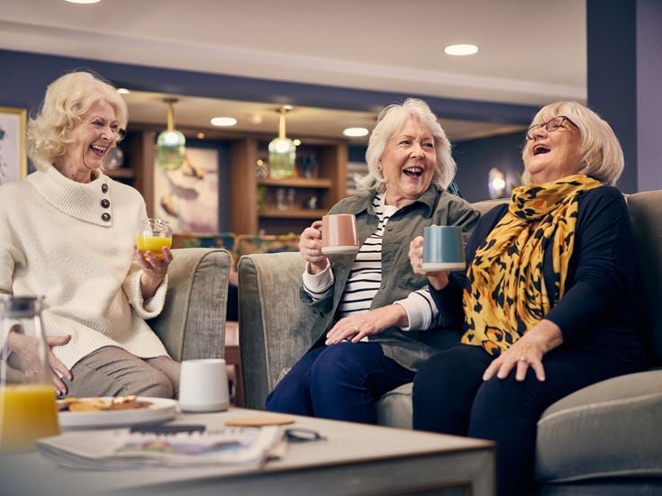 a group of women sitting on a couch and laughing