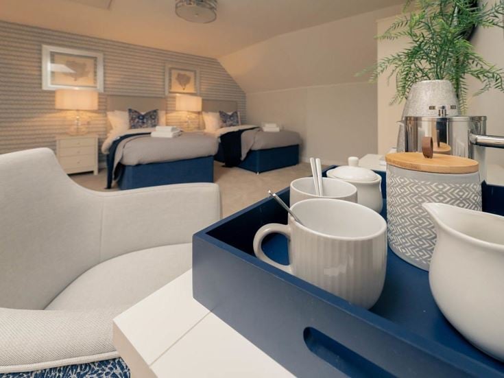a white coffee table with a blue couch and white coffee cups on it