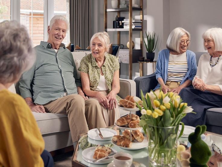 a group of elderly women sitting around a table with food
