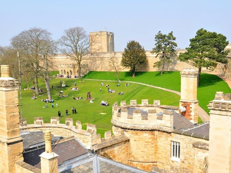 People on the lawn of Lincoln Castle surrounded by the medieval walls.