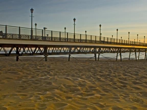 Skegness Pier at sunset on the Lincolnshire coast, with orange clouds over the ocean on the horizon.