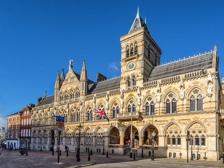 A photo of Northampton Guildhall, a Victorian brick building with many archways.