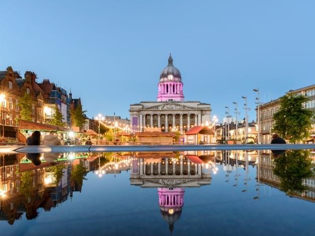 Nottingham Council House during twilight hours, with its reflection shown in a fountain in Old Market Square.