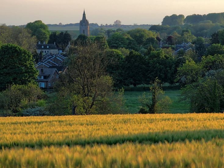 A field lit up by a sunset, village in the distance, in Rutland.