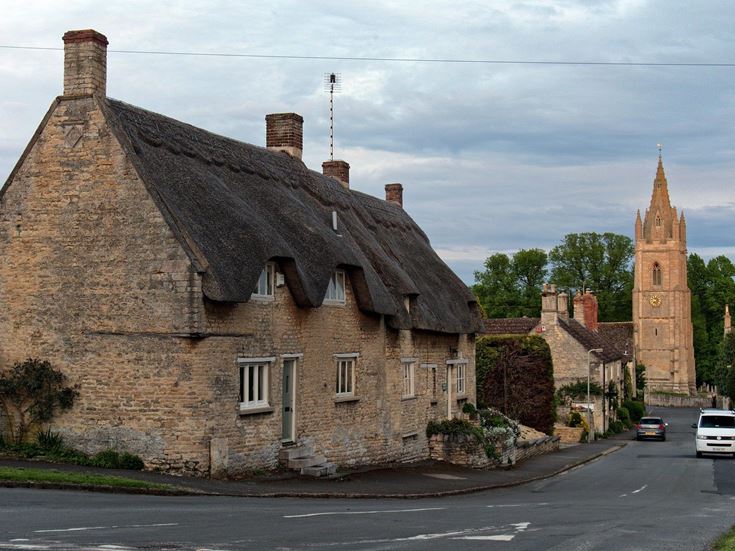 Houses with thatched roofing and a gothic-style church in a small town in Rutland.