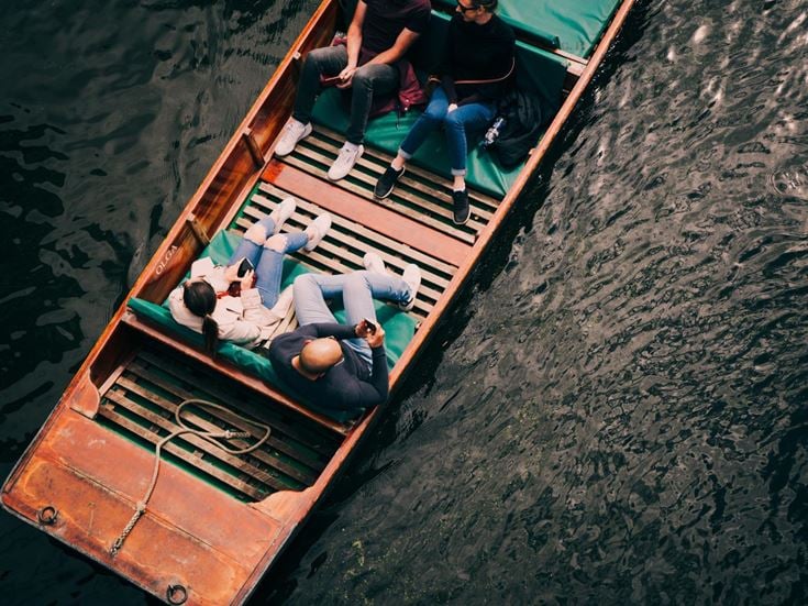 A group of people in a punt on the River Cam, enjoying the scenery.