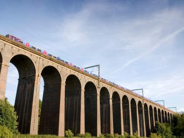 Digswell Viaduct in Hertfordshire, with a train moving along it set against a blue sky.