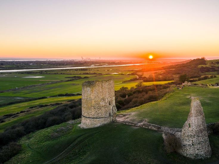 An orange sunset over rolling green Essex countryside and the ruins of Hadleigh Castle.
