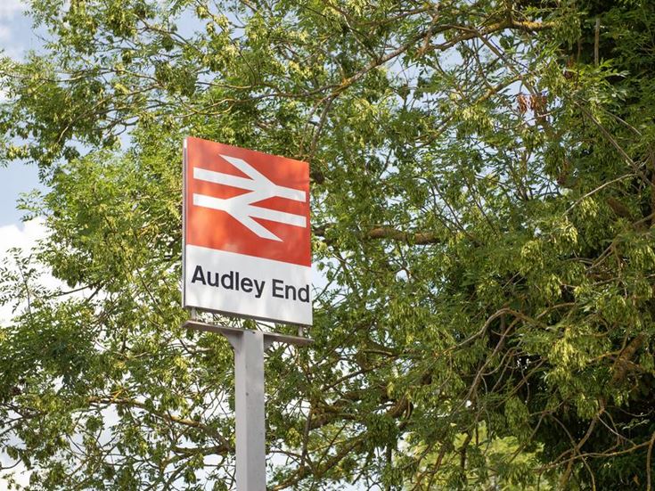 A road sign in front of a tree. The sign has the National Rail logo and says ‘Audley End’.