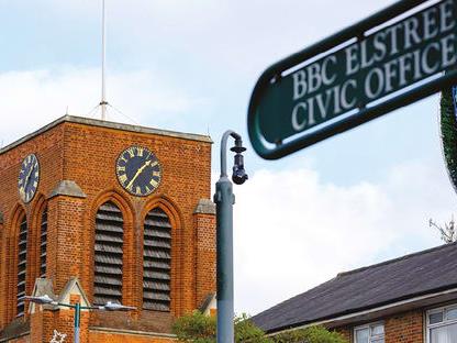 All Saints Church behind a street sign for BBC Elstree Studios and Civic Offices.