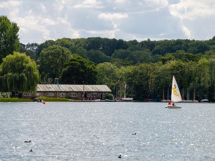 A small boat sails towards the shore on a large lake in Rickmansworth.