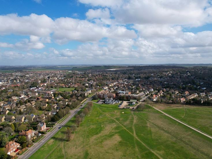 a large green field with buildings and trees around it