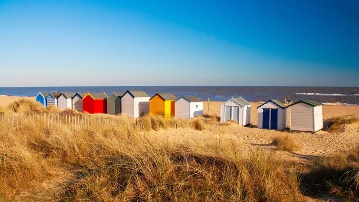 A row of colourful beach huts looking out to see in Southwold, Suffolk.