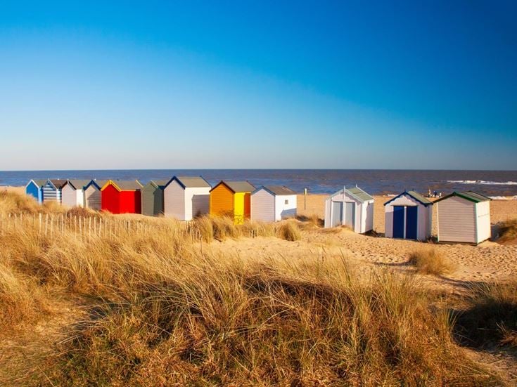 A row of colourful beach huts looking out to see in Southwold, Suffolk.