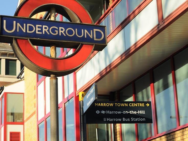 The London Underground sign in Harrow, and a signpost for the bus station and train station.