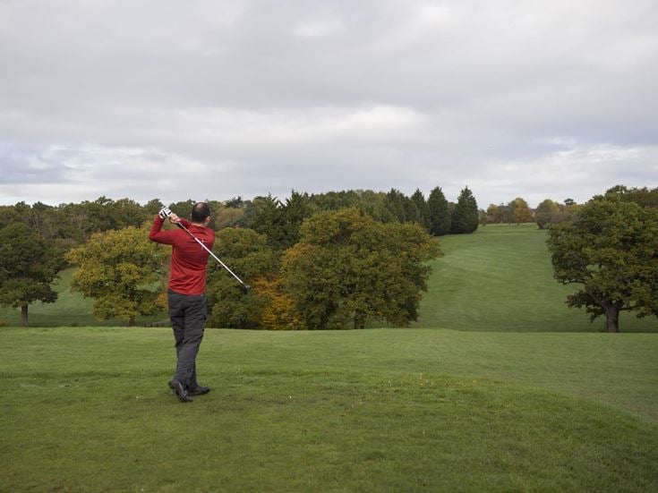A man swinging a golf club at Trent Park Golf Club.