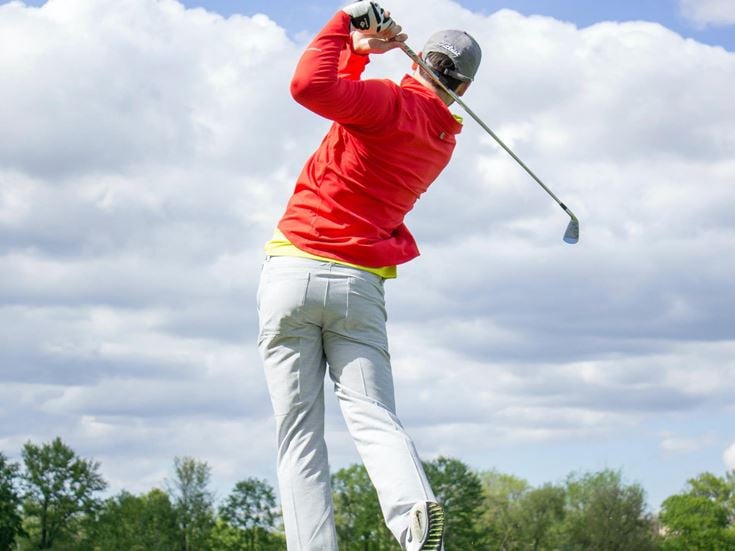 A retiree in the middle of a golf swing, cloudy sky in the background.