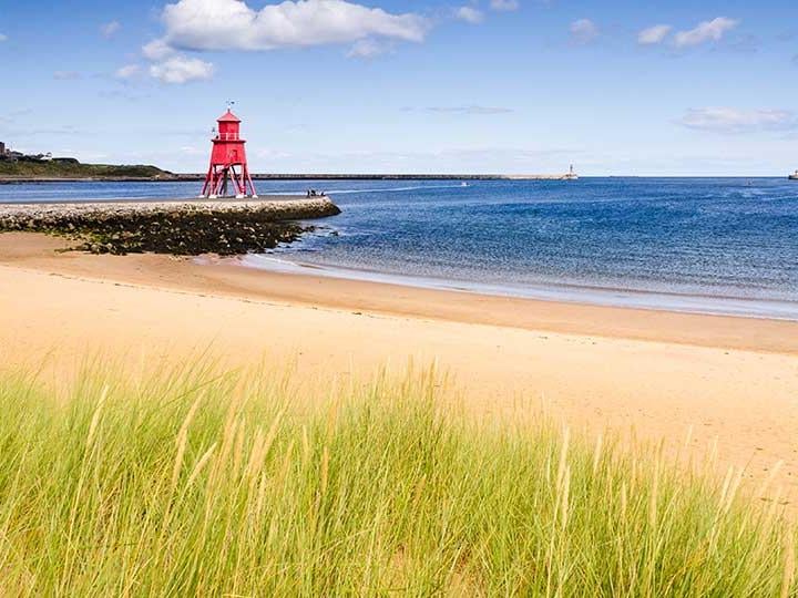 a beach with a red tower and water in the background