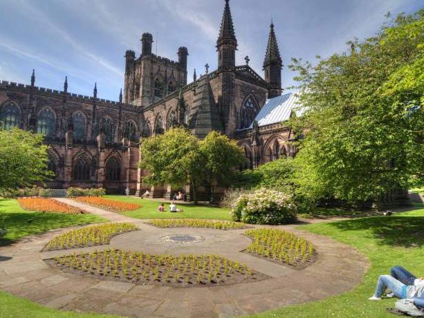 Exterior of Chester Cathedral with people relaxing in its courtyard.