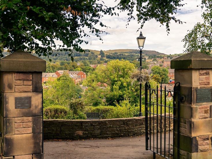 A gate with a stone wall with the town market town of Macclesfield in the background