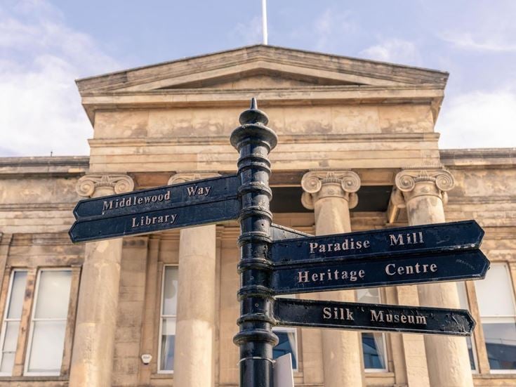 A signpost in Macclesfield centre, pointing to the library, silk museum, and heritage centre.