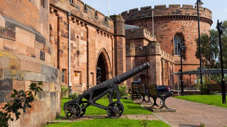 Carlisle Citadel’s striking red sandstone walls and historic cannon on a sunny day in the city.