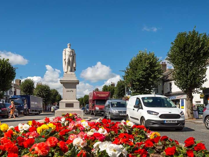 a group of cars parked on the side of a road with flowers and a statue on top of