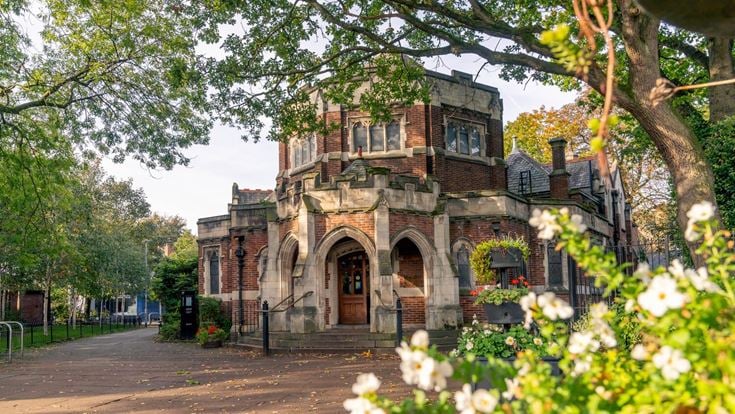 A large brick building with a large arched doorway in the centre of Didsbury, Greater Manchester