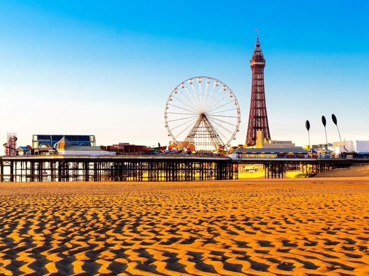 Blackpool beach, with the pier, a ferris wheel and Blackpool Tower in the background.