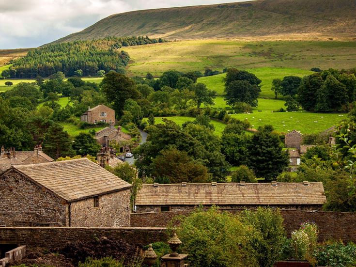 Downham village near Clitheroe in the countryside with towering hills in the background.