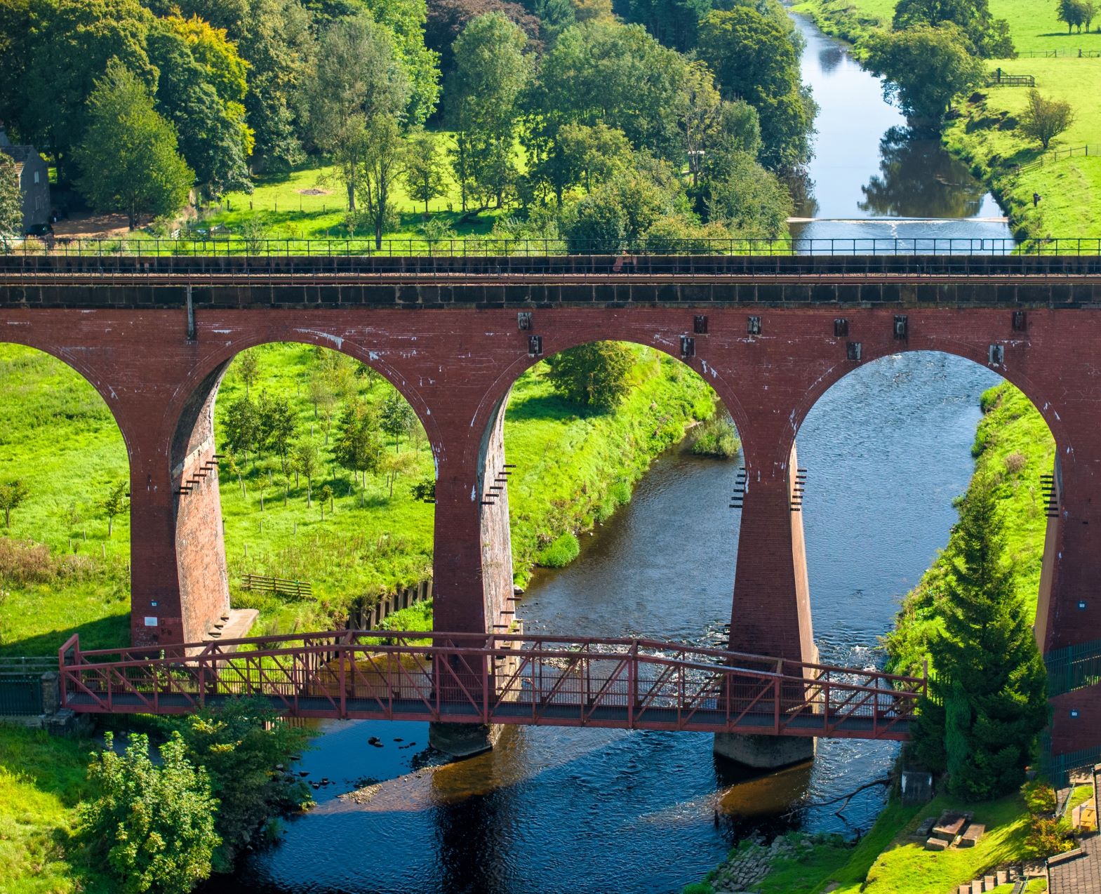 Whalley Arches viaduct over the river Calder between two fields in Lancashire.