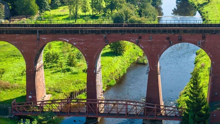 Whalley Arches viaduct over the river Calder between two fields in Lancashire.