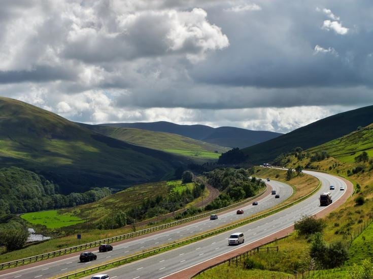 Vehicles on the M6 motorway cutting through hills in Cumbria.