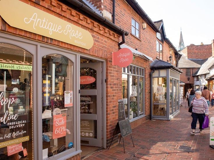 A retired lady walks outside various shops in Wokingham centre.