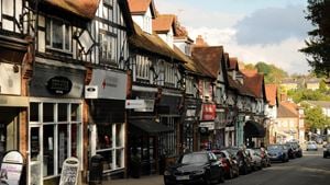 A main road with cars, lined with shops and Tudor-style buildings.