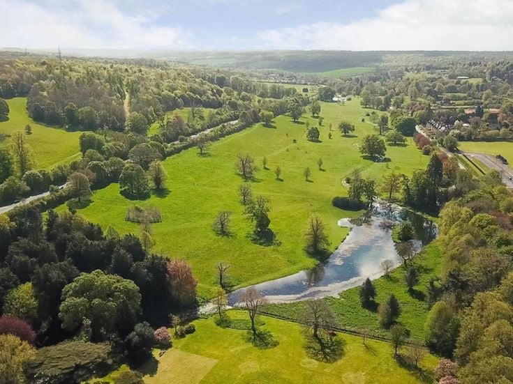 An aerial view of rolling green hills, a road and a lake in Great Missenden.