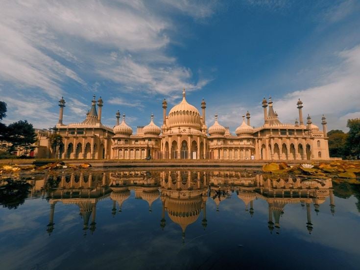 The grand exterior of Royal Pavilion in Brighton, reflected in the water below.