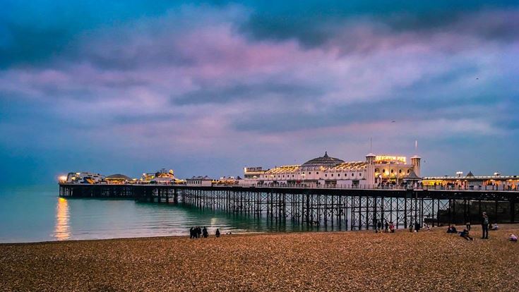 Brighton Palace Pier in Brighton seen from the beachfront during twilight hours.