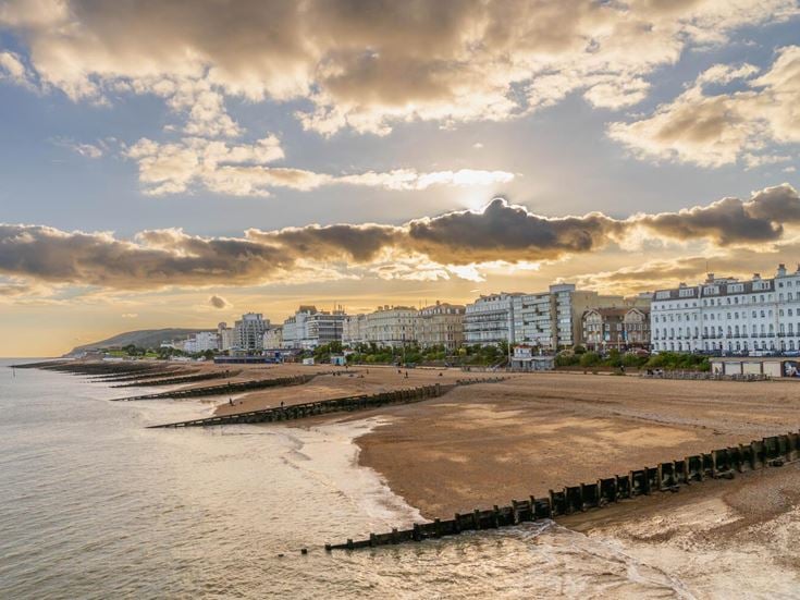 A beach in Eastbourne at sunset with buildings along the seafront.