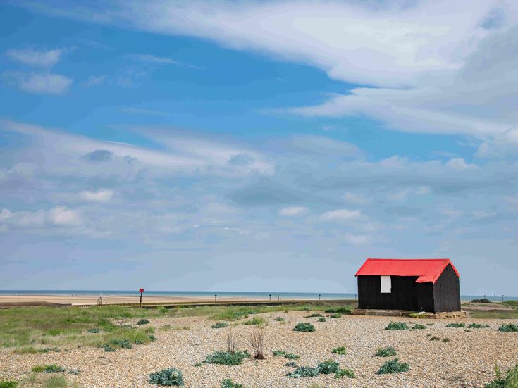 A red roofed hut on the Rye Harbour estuary in East Sussex.