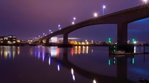 Itchen Bridge over still water in Southampton at night, with light reflected on the water.