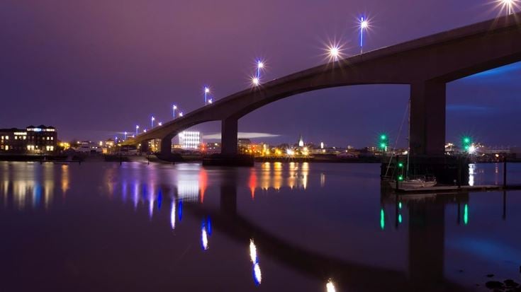 Itchen Bridge over still water in Southampton at night, with light reflected on the water.