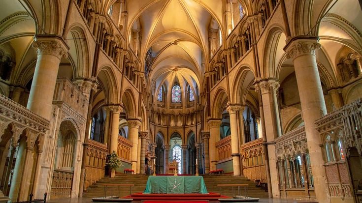 Inside Canterbury Cathedral, with an altar and red carpet.